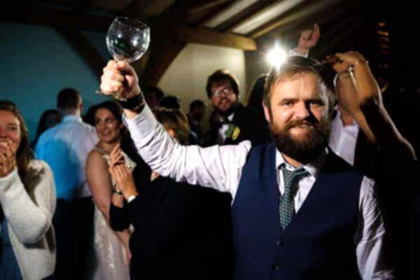 Man raising glass at lively gathering.