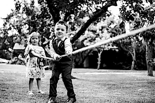 A black and white photo capturing the joyful play of two children with a rope, taken by a talented Dodford Manor Wedding Photographer.