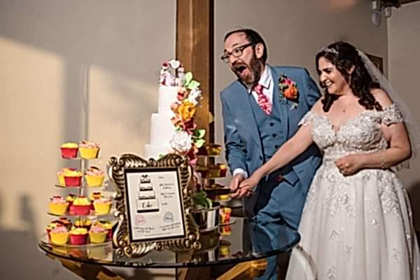 A bride and groom cutting their wedding cake at Dodford Manor captured by a professional Wedding Photographer.