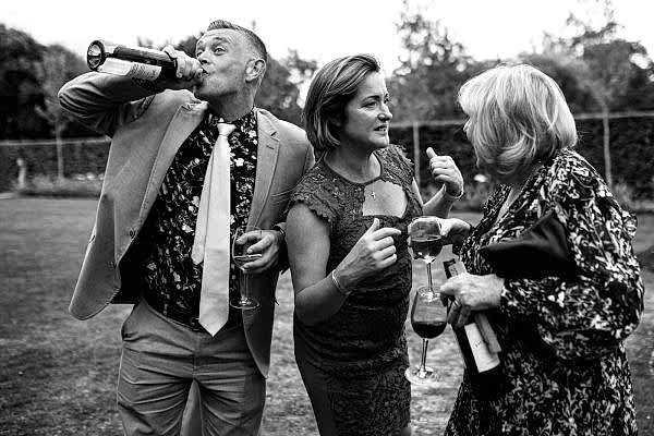 A group of people at a wedding, captured by the Dodford Manor Wedding Photographer while enjoying wine.