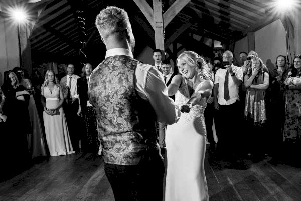 A bride and groom sharing their first dance in a barn captured by Dodford Manor Wedding Photographer.