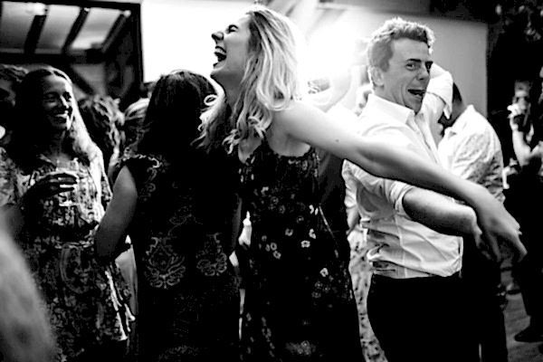 A black and white photo capturing the joyous celebration of people dancing at a Dodford Manor wedding.