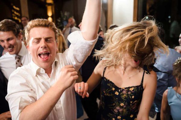 A lively group of people dancing at a Dodford Manor wedding reception.