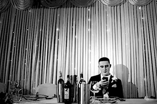 A Dodford Manor Wedding Photographer capturing a man sitting at a table engrossed in his phone.