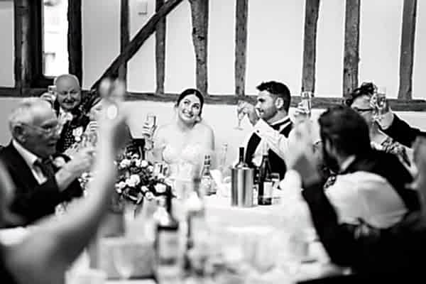 A black and white photo of people toasting at a Dodford Manor wedding.