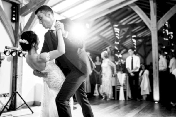 Dodford Manor Wedding Photographer captures the magical moment of a bride and groom sharing their first dance in a rustic barn setting.