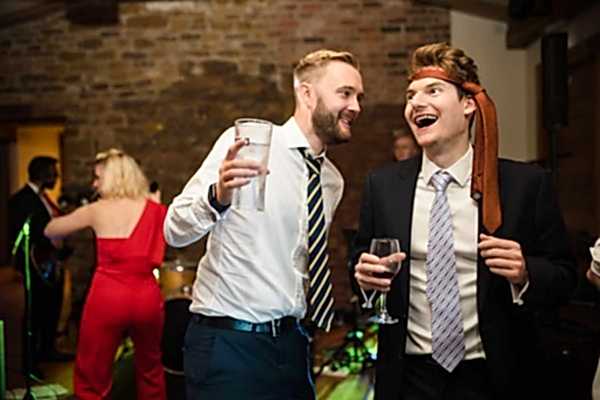 Dodford Manor Wedding Photographer capturing two men laughing at a wedding reception.