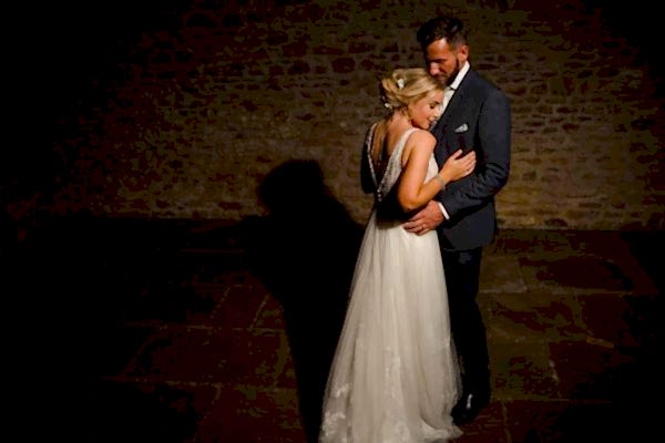 Dodford Manor Wedding Photographer: Capturing an intimate moment amidst dimly-lit surroundings, this image portrays a tender embrace between a bride and groom.
