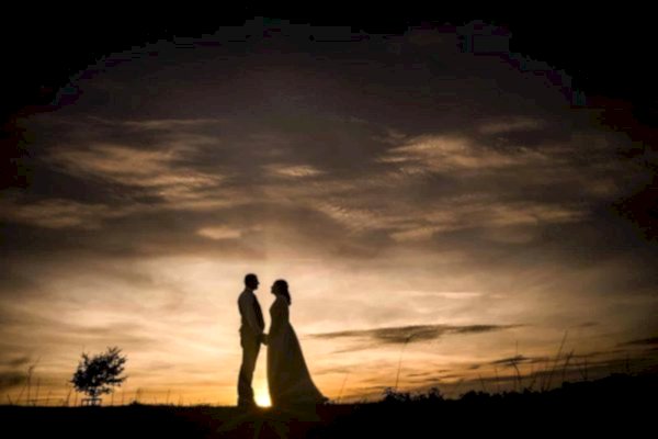 A breathtaking silhouette of a bride and groom at sunset captured by Dodford Manor Wedding Photographer.