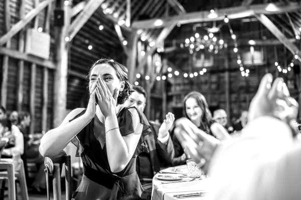 A bride and groom clapping at a Dodford Manor wedding reception, captured by a talented Dodford Manor Wedding Photographer.