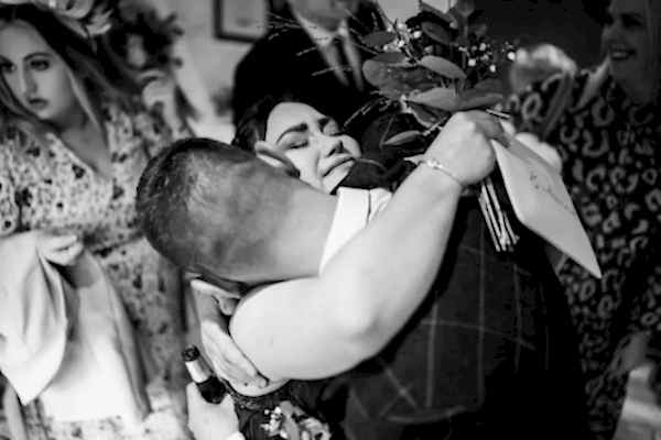 Dodford Manor Wedding Photographer captures a striking black and white photo of a woman embracing a man in an intimate moment.