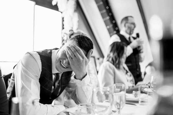 A Dodford Manor Wedding Photographer capturing a man with his face covered at a wedding.