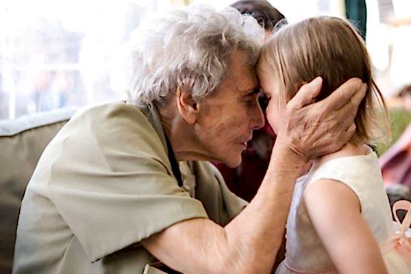 Dodford Manor Wedding Photographer captures a heartwarming moment as a little girl lovingly embraces an older woman.