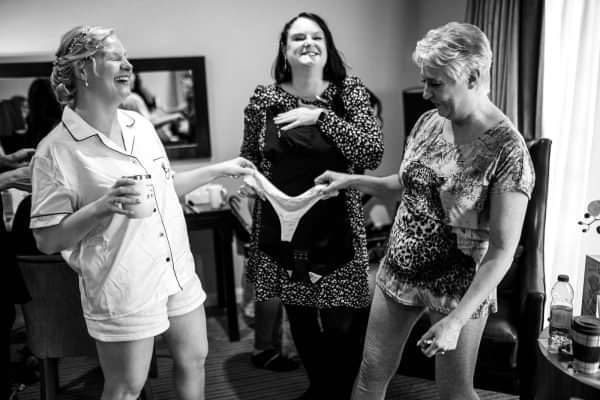 A bride getting ready in a hotel room with her bridesmaids for her Dodford Manor Wedding.