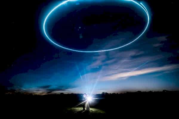 A Dodford Manor wedding photographer capturing a man standing in a field with a circle in the sky.