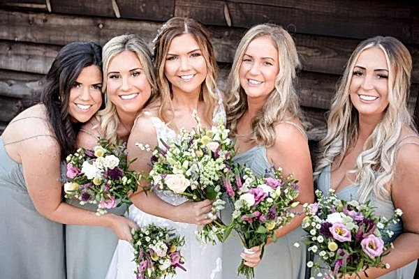 Dodford Manor Wedding Photographer capturing bridesmaids holding bouquets in front of a wooden wall.