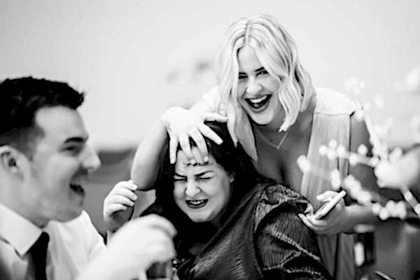 A black and white photo of a group of people laughing, captured by a Dodford Manor Wedding Photographer.