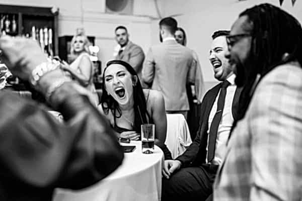 Dodford Manor Wedding Photographer capturing a group of people laughing at a party.