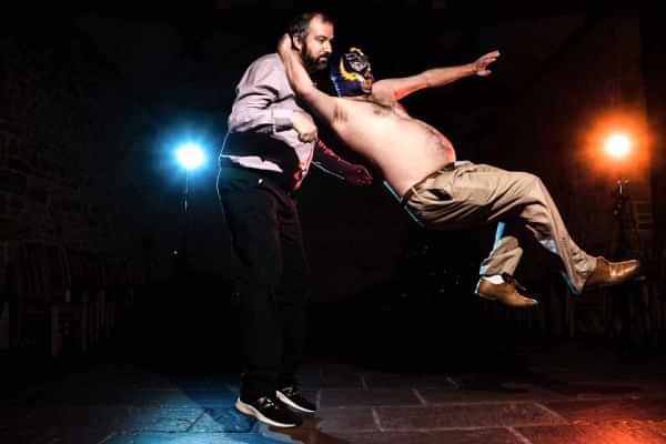 Two men, captured beautifully by a Dodford Manor wedding photographer, showcasing their incredible acrobatics in a dark room.