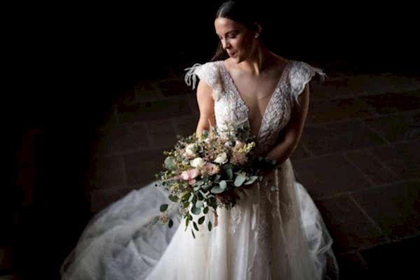 A bride holding a bouquet in a dark room captured by the Dodford Manor Wedding Photographer.