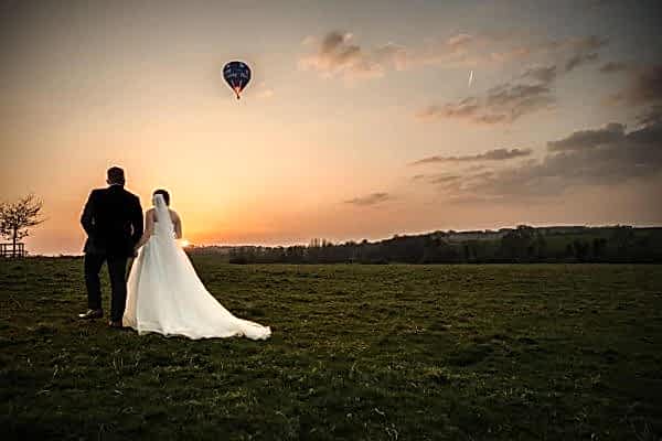 Wedding couple watching sunset and hot air balloon.