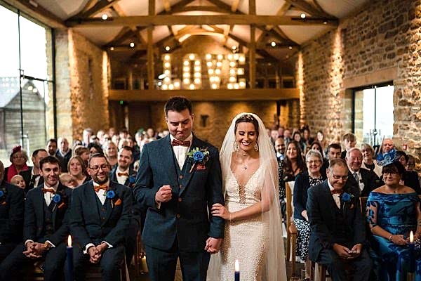 Dodford Manor Wedding Photographer capturing a beautiful bride and groom walking down the aisle at their wedding.