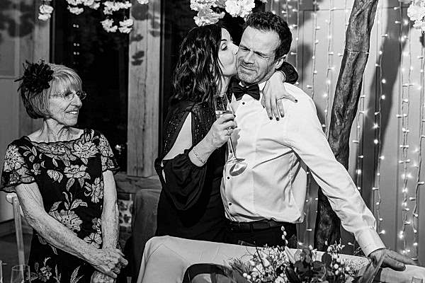 A Dodford Manor Wedding Photographer captures a heartfelt kiss between a man and woman at their wedding reception.