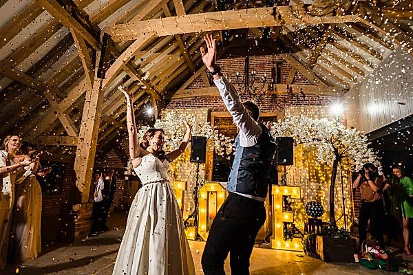 A Dodford Manor wedding photographer captures the joyful moment of a bride and groom throwing confetti at their reception.