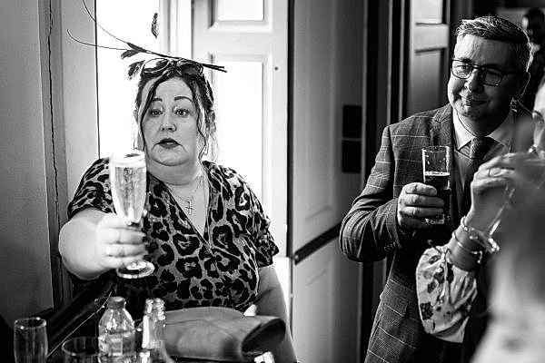 A black and white photo of a woman holding a glass of wine, captured by an expert Dodford Manor Wedding Photographer.