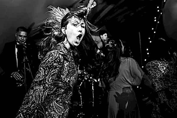 A black and white photo of a woman singing in a band captured by Dodford Manor Wedding Photographer.