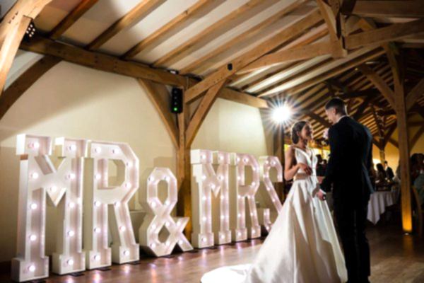 A Dodford Manor Wedding Photographer captures the special moment of a bride and groom standing in front of Mr and Mrs letters.