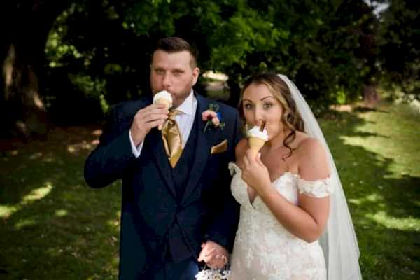 A Dodford Manor Wedding Photographer captures a moment of a bride and groom enjoying an ice cream cone.