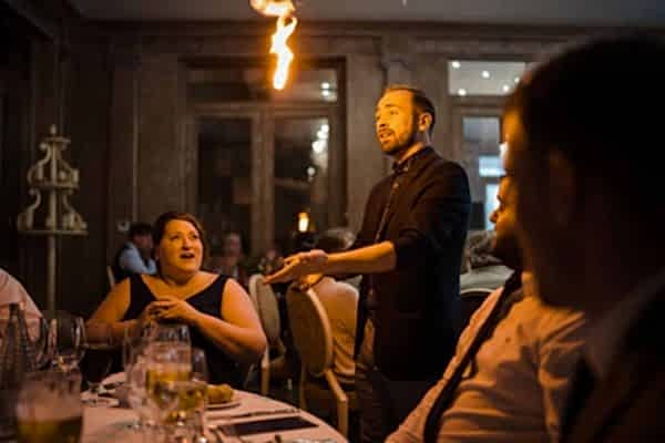 The Dodford Manor Wedding Photographer captured a man igniting a fire in front of a group of people.