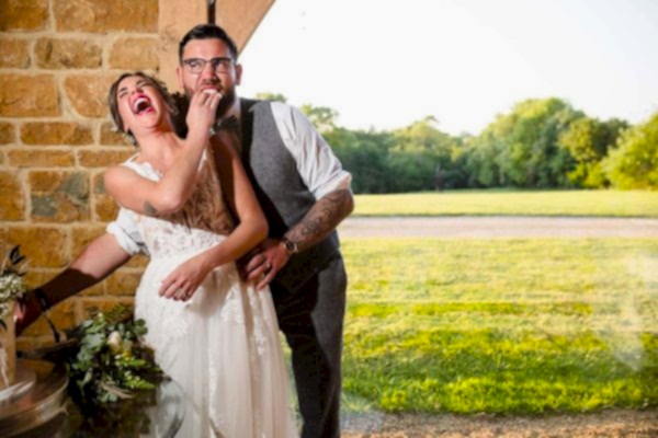A bride and groom laughing while cutting their wedding cake captured by a Dodford Manor Wedding Photographer.