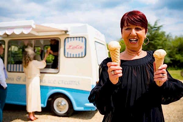 A woman holding an ice cream cone in front of an ice cream van at Dodford Manor.