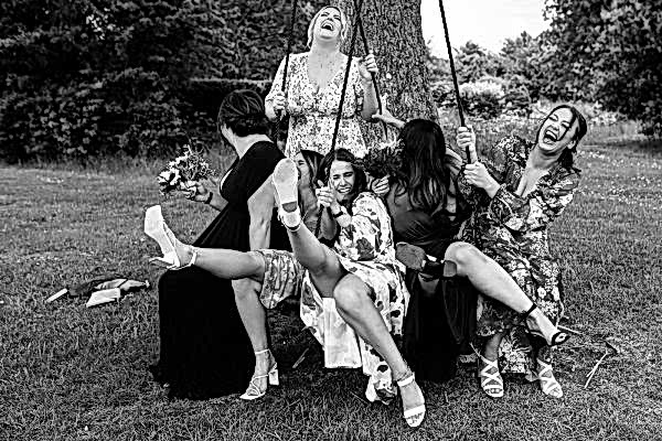 A stunning black and white photo of bridesmaids on a swing, captured by the talented Dodford Manor Wedding Photographer.