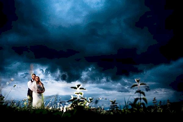 A Dodford Manor wedding photographer capturing a bride and groom standing under a stormy sky.