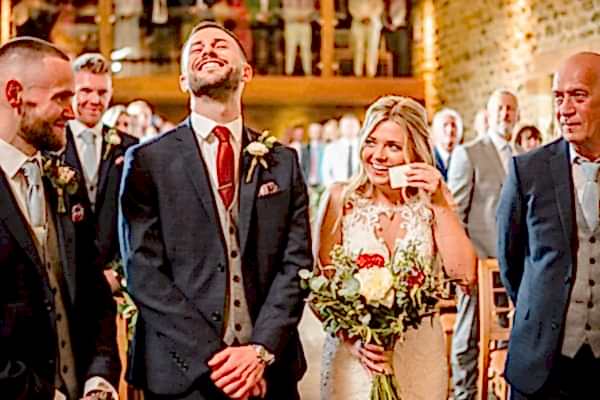 A Dodford Manor wedding photographer captures the joyful moments as the bride and groom laugh at each other during their ceremony.