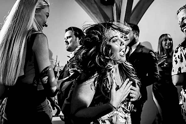Dodford Manor Wedding Photographer captures a mesmerizing black and white photo of a group of people joyously dancing at a wedding.