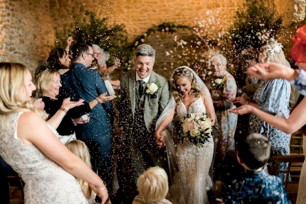 A Dodford Manor Wedding Photographer captures the magical moment of a wedding ceremony as confetti is joyfully thrown at the bride and groom.
