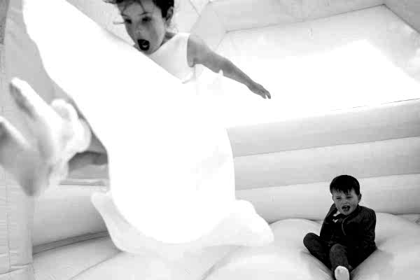 A boy and girl enjoying a white bouncy castle at Dodford Manor Wedding.