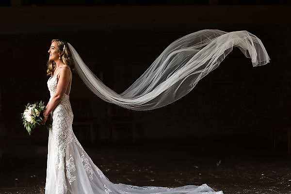 A Dodford Manor Wedding Photographer captures a bride with her veil blowing in the wind.