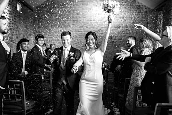 Dodford Manor Wedding Photographer: Capture the magical moment of a bride and groom walking down the aisle, surrounded by joyful confetti.